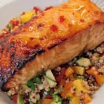 Salmon dinner - cooked piece of salmon on a bed of quinoa salad with mango