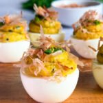 Four egg whites, filled with the yolk mix and topped with chopped chives and bonito flakes. Served on a wooden board