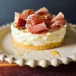 Round white plate with the no-bake cheesecake with pear and prosciutto on top