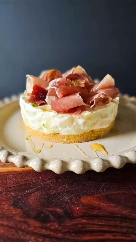 Round white plate with the no-bake cheesecake with pear and prosciutto on top