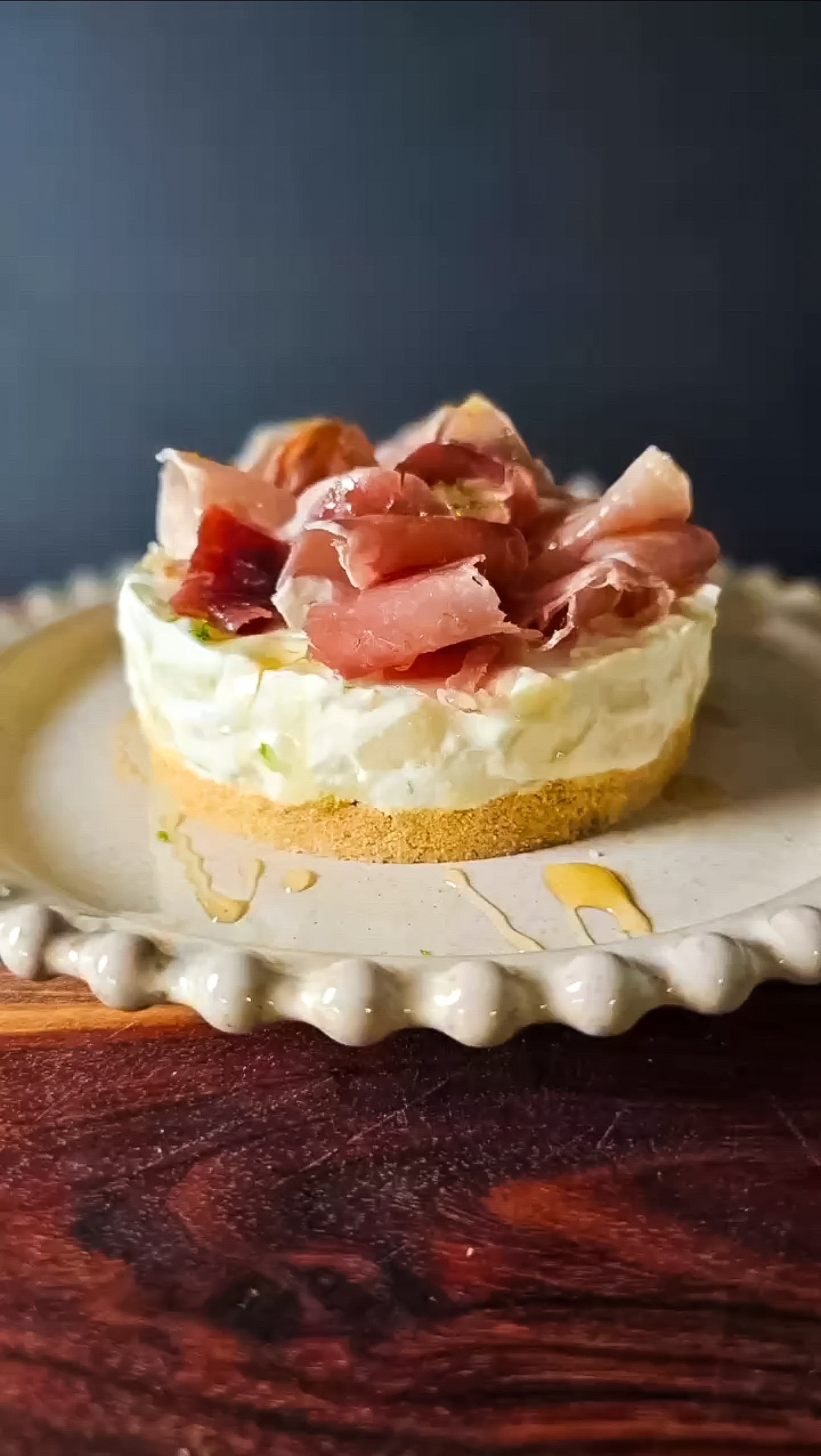 Round white plate with the no-bake cheesecake with pear and prosciutto on top