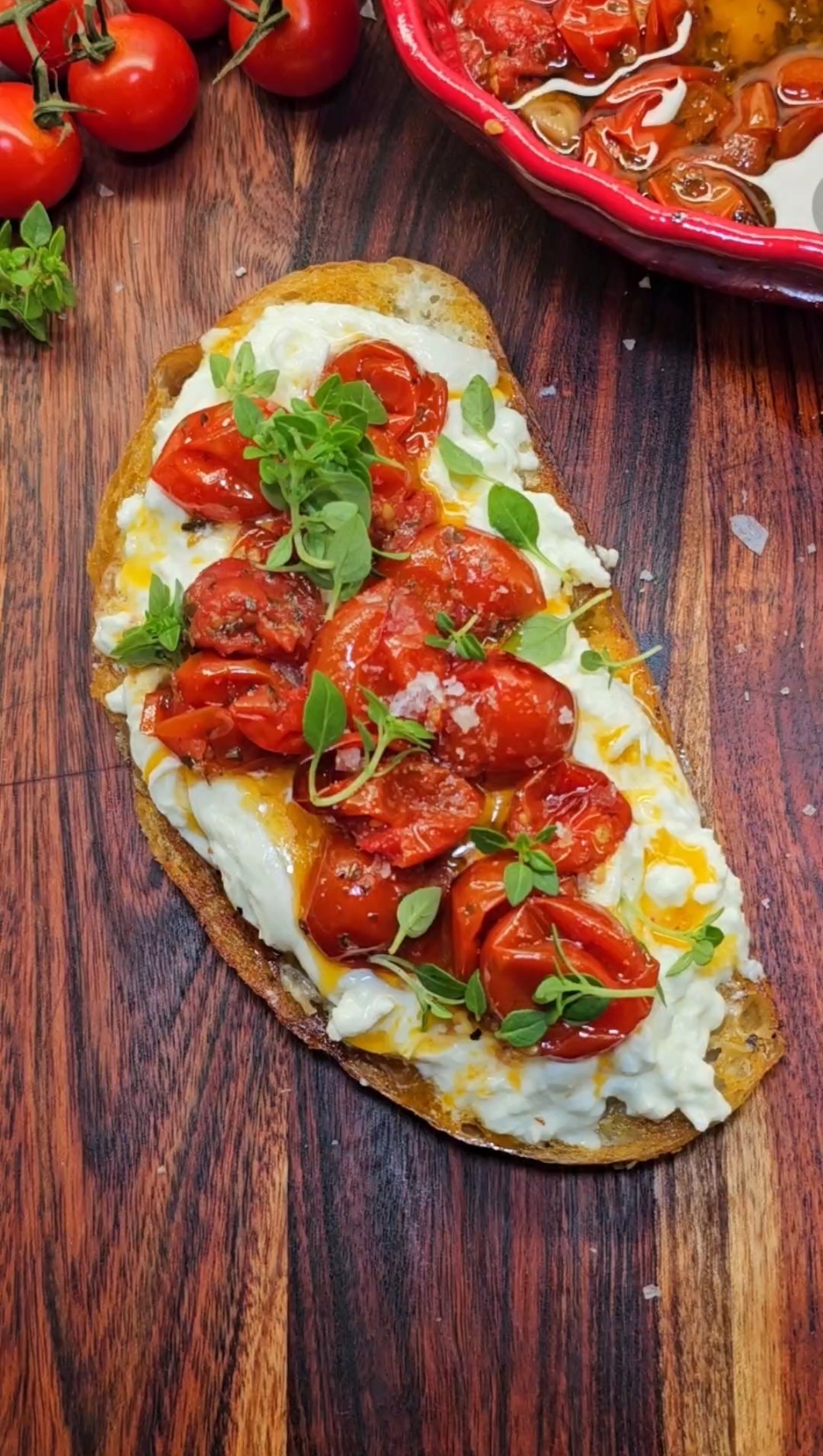 Toast with burrata and roasted tomatoes, served on a wooden board
