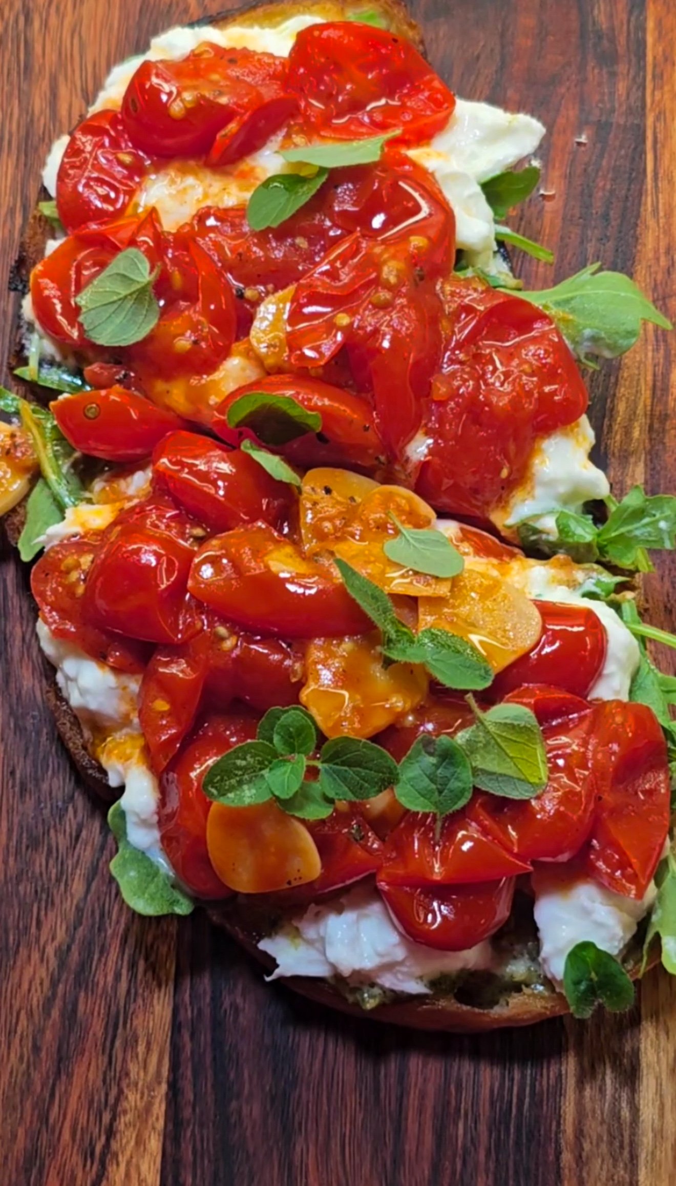 wooden board with toast, topped with cooked tomatoes