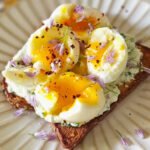 Toast with chive ricotta and soft boiled eggs on a white round plate