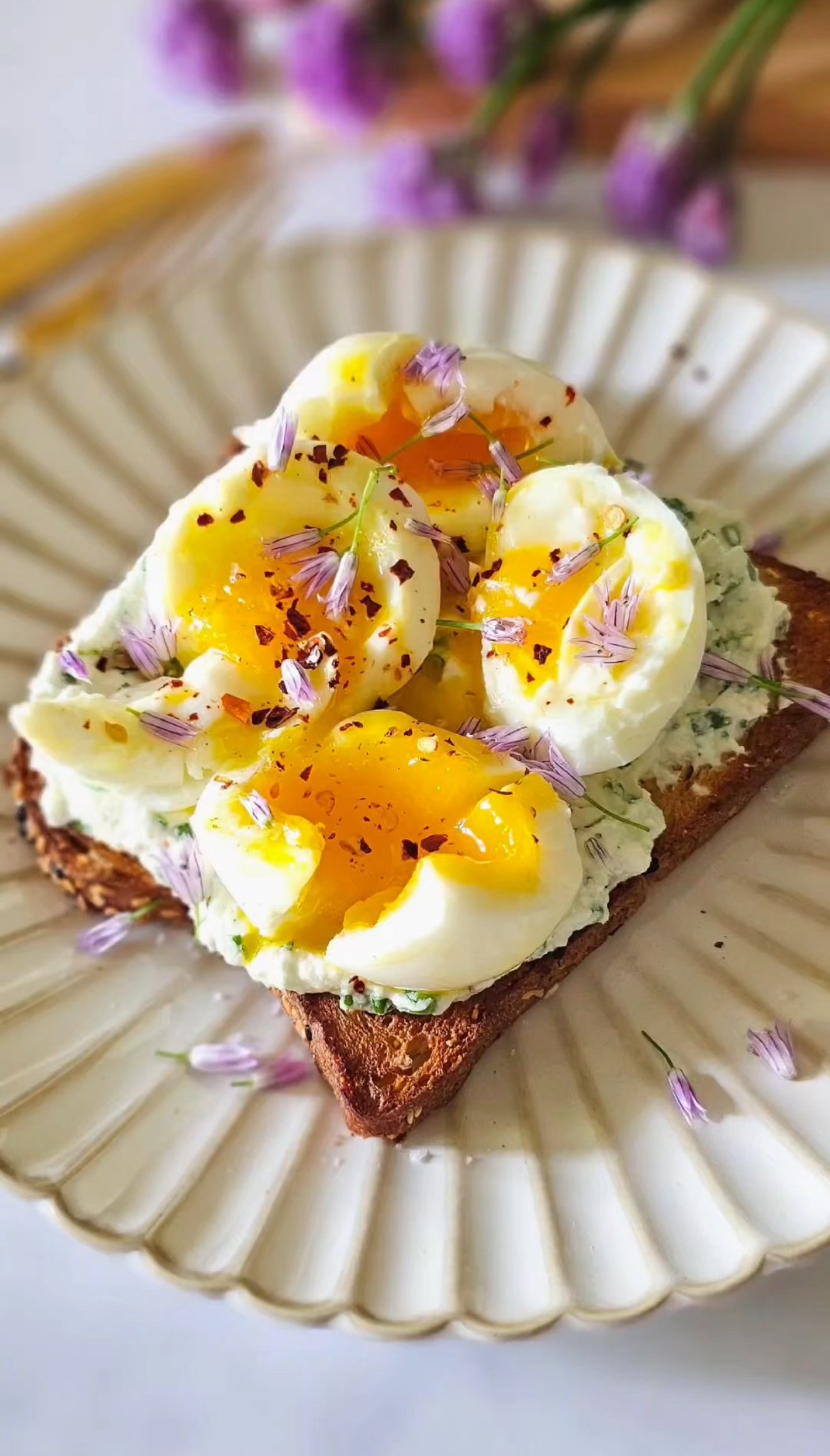 Toast with chive ricotta and soft boiled eggs on a white round plate