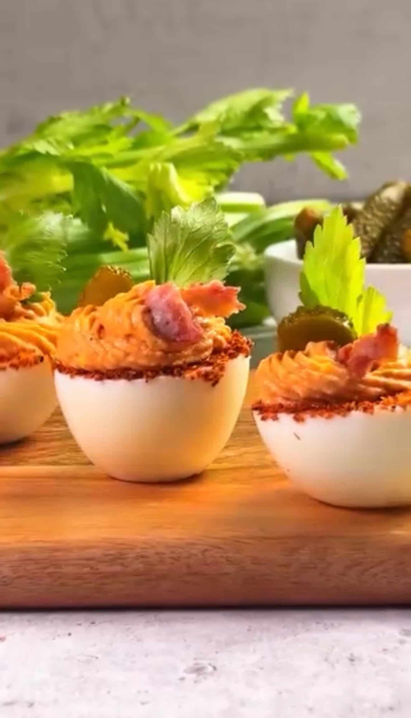 Three egg whites, filled with the yolk mix and decorated with a slice of pickle, bacon and celery leaf
