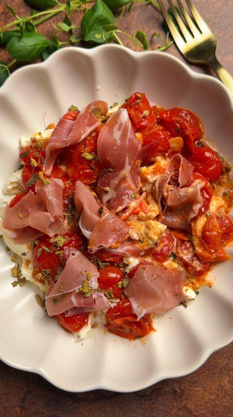 Burrata, topped with tomatoes and prosciutto in a bowl