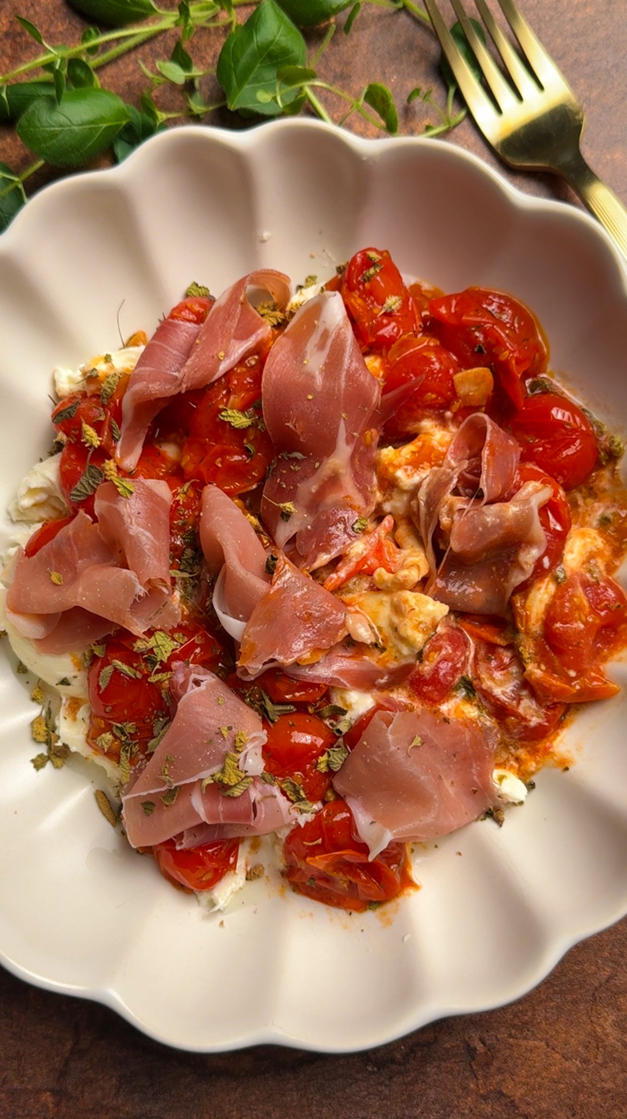 Burrata, topped with tomatoes and prosciutto in a bowl