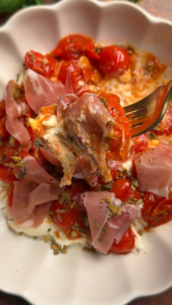 Burrata with tomatoes and prosciutto on a fork