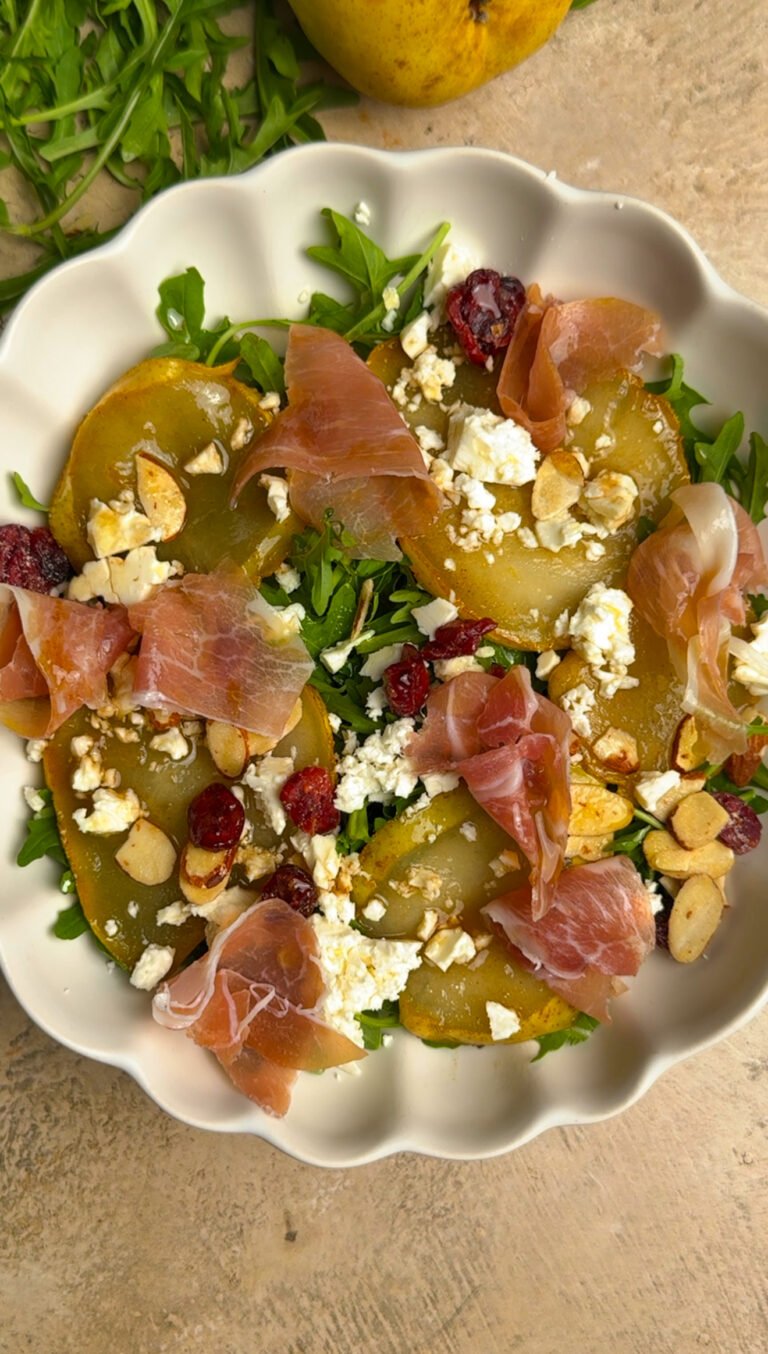 Salad with prosciutto and pear on a white plate