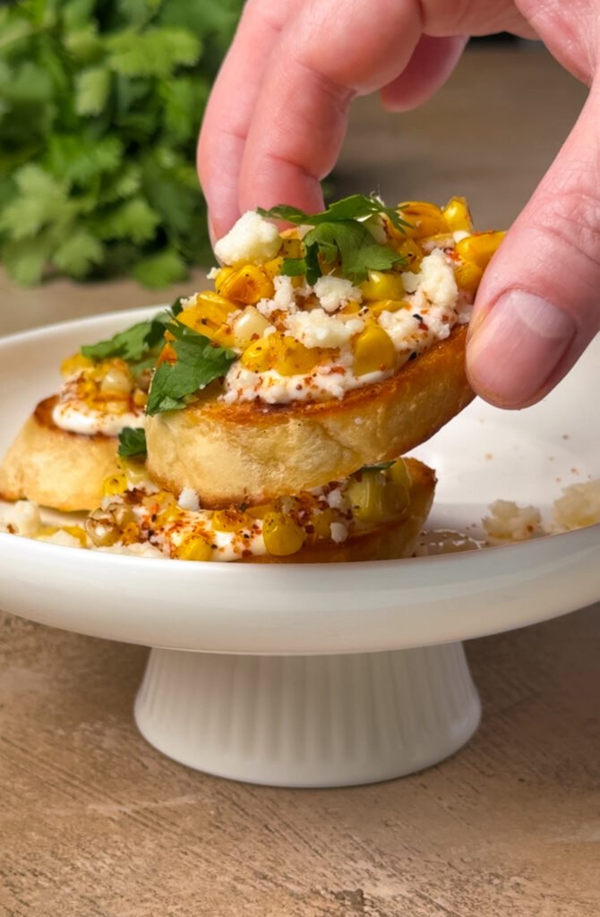 Mexican Street Corn Ricotta Tartines - hand is holding one of them