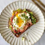 Round plate with toast, topped with egg with broken yolk