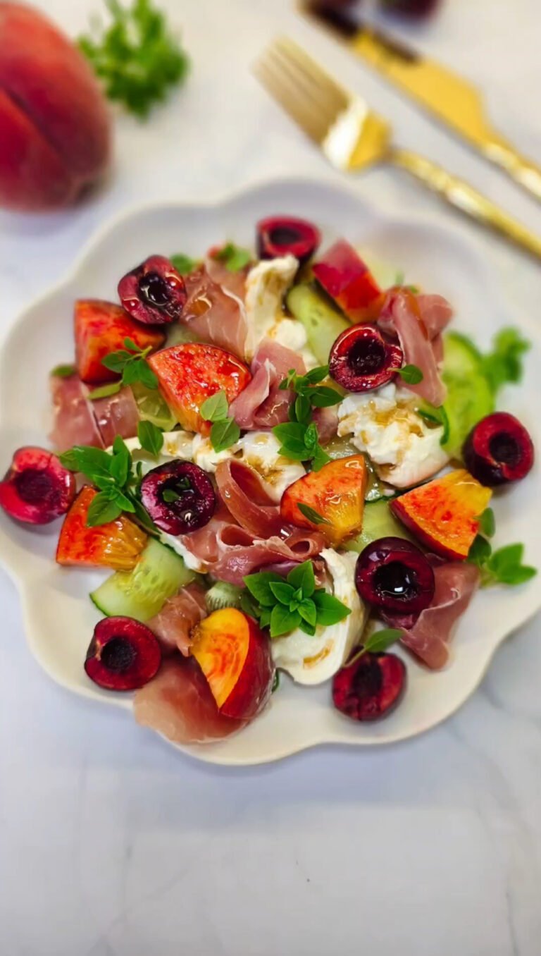Salad with peach, cherry, cucumber and prosciutto in a round plate