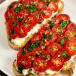 Two toast with tomatoes on a white round plate