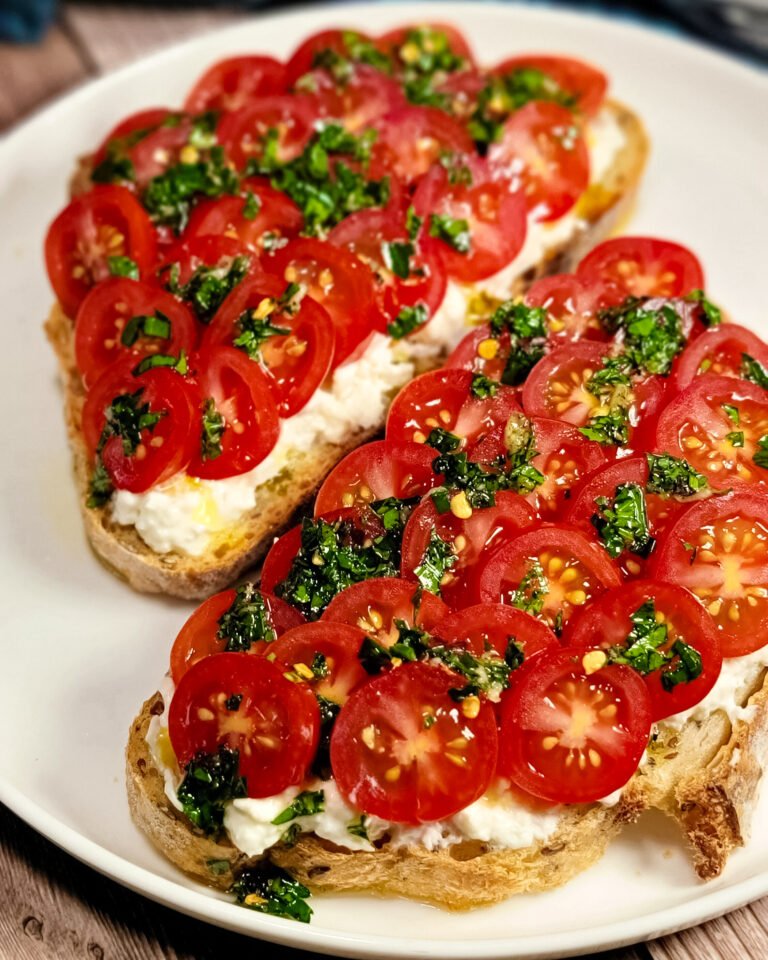 Two toast with tomatoes on a white round plate