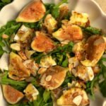 Salad with fresh figs, arugula and cheese on a round plate