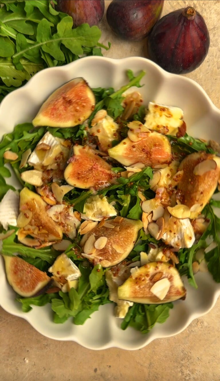 Salad with fresh figs, arugula and cheese on a round plate