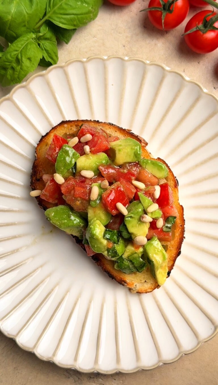 Toast with tomato and avocado on a white round plate