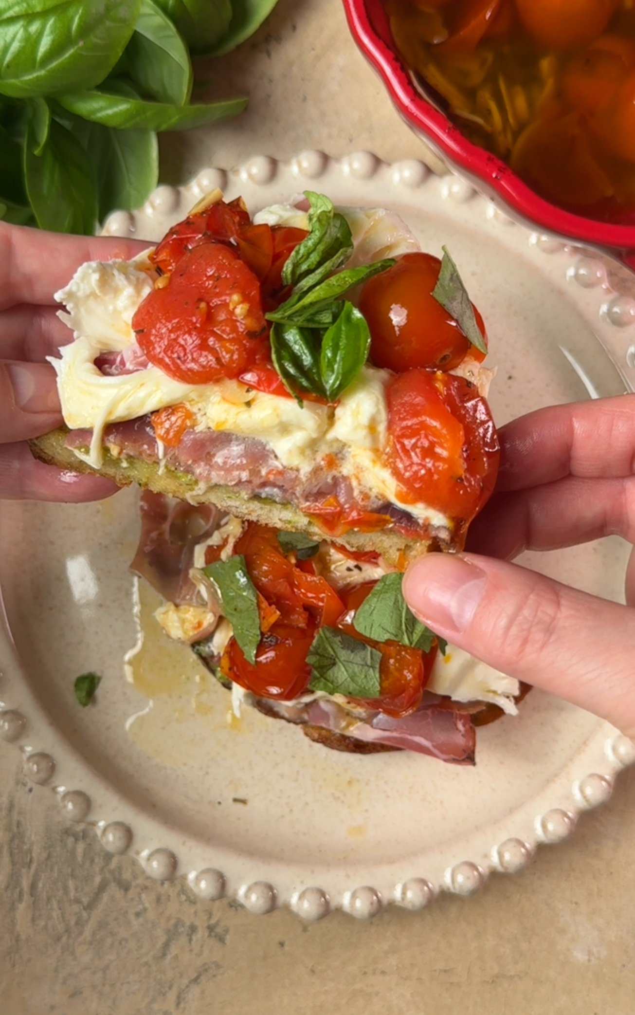 Hand is holding a piece of toast with tomatoes