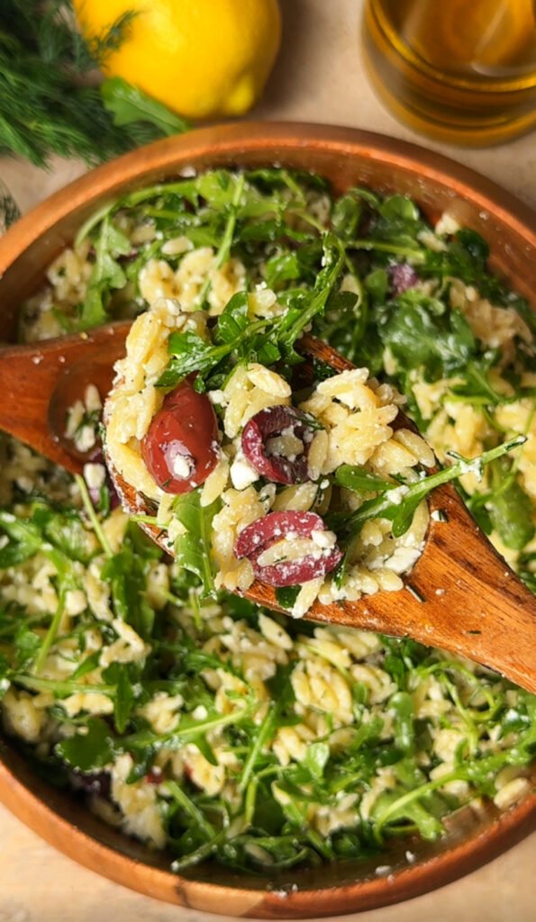 Lemon-Dill Orzo Salad in a wooden bowl. Spoon is on top with some salad