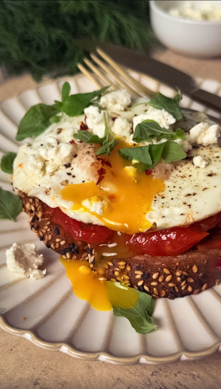 Breakfast toast, topped with fried egg on a white plate