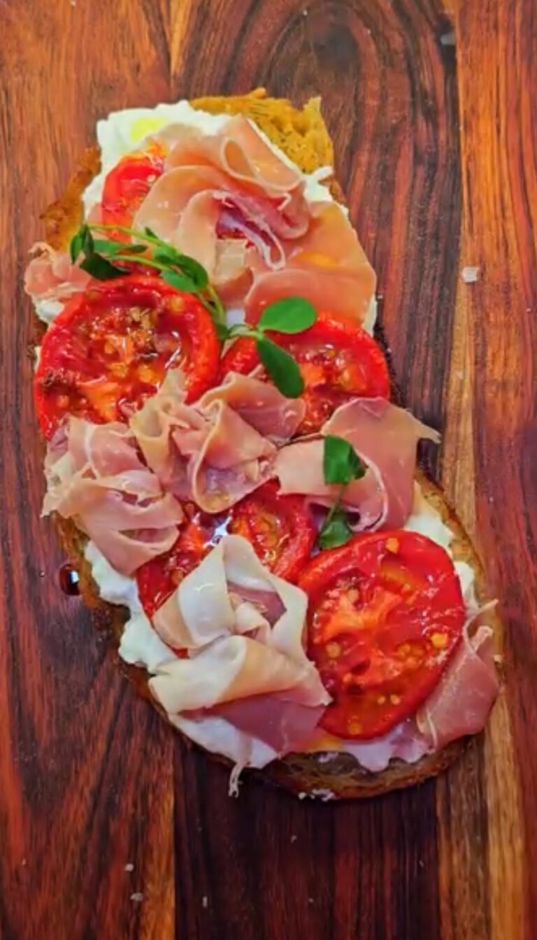 Stracciateklla toast with tomatoes on a wooden board