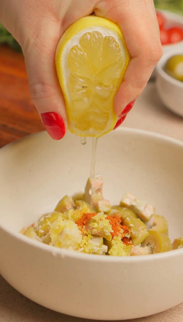 Olive mix in a bowl, Hand is squeezing the lemon