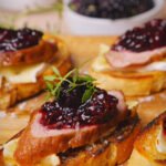 Crostini with duck and blackberry jam on a wooden board