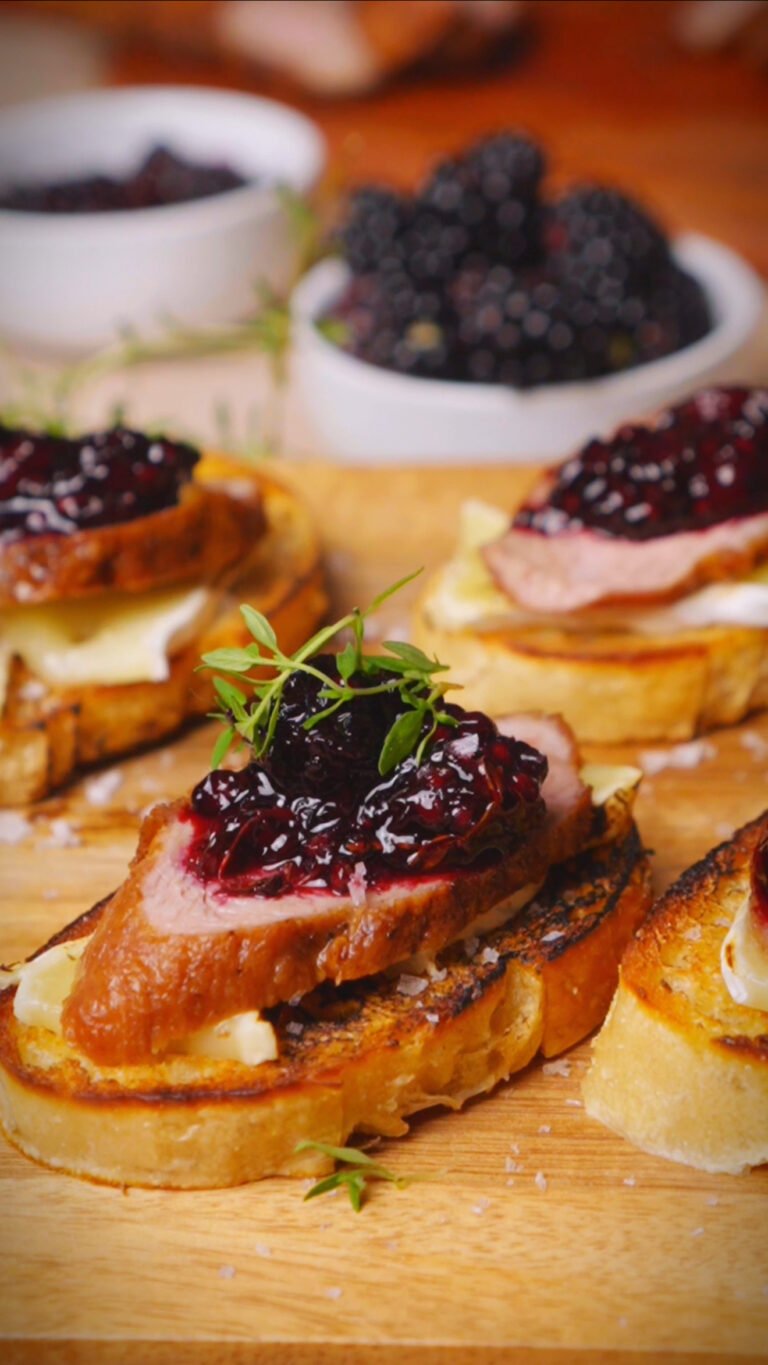 Crostini with duck and blackberry jam on a wooden board