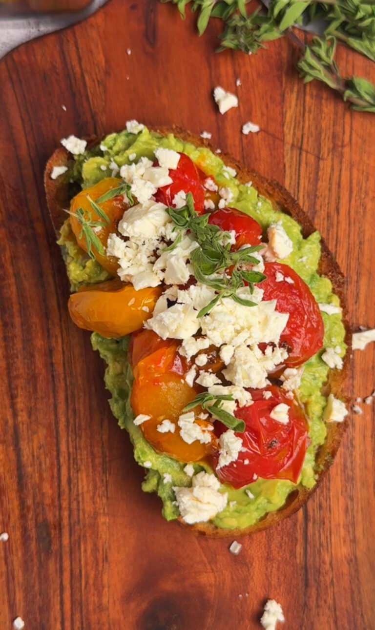 Close-up of toast with basil pesto, avocado, blistered cherry tomatoes and feta crumbs