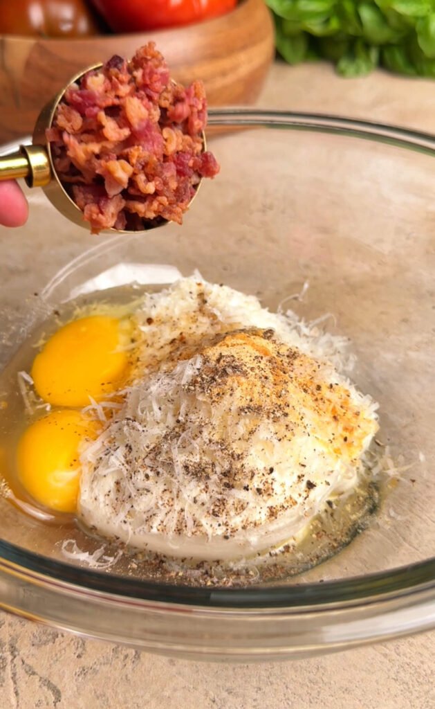 Mixing ricotta cheese, Parmesan, eggs, and crispy bacon in a glass bowl for savory heirloom tomato pie filling