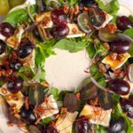 Finished salad wreath with grapes, Brie, red onion, toasted walnuts, and chili threads, styled elegantly