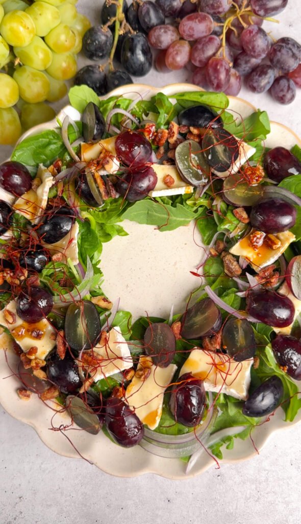 Finished salad wreath with grapes, Brie, red onion, toasted walnuts, and chili threads, styled elegantly