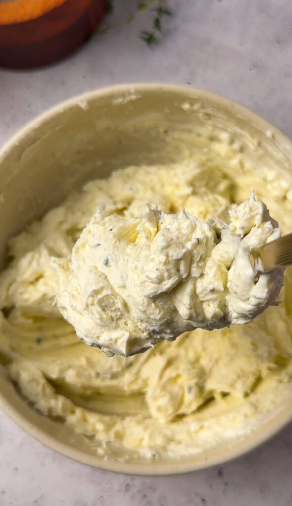 A fluffy, whipped truffle-thyme goat cheese mixture on a spoon, showing its light, creamy texture