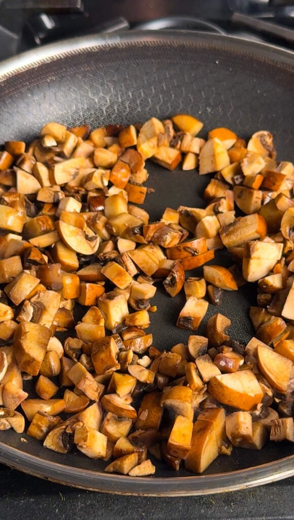 Pan-fried mushrooms and shallots starting to caramelize, turning glossy and golden