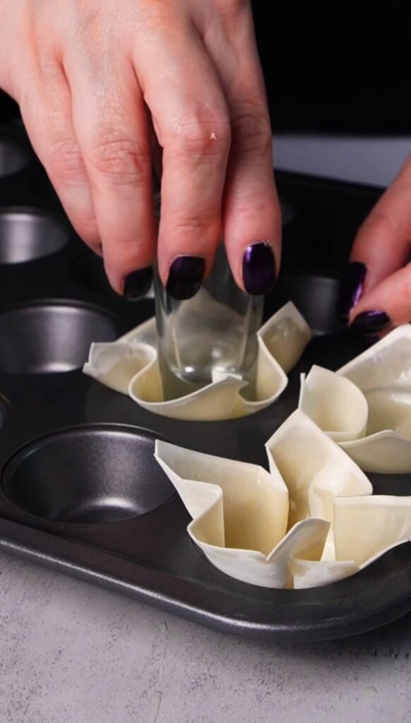 Wonton wrappers pressed into a mini muffin pan to create crispy baked wonton cups