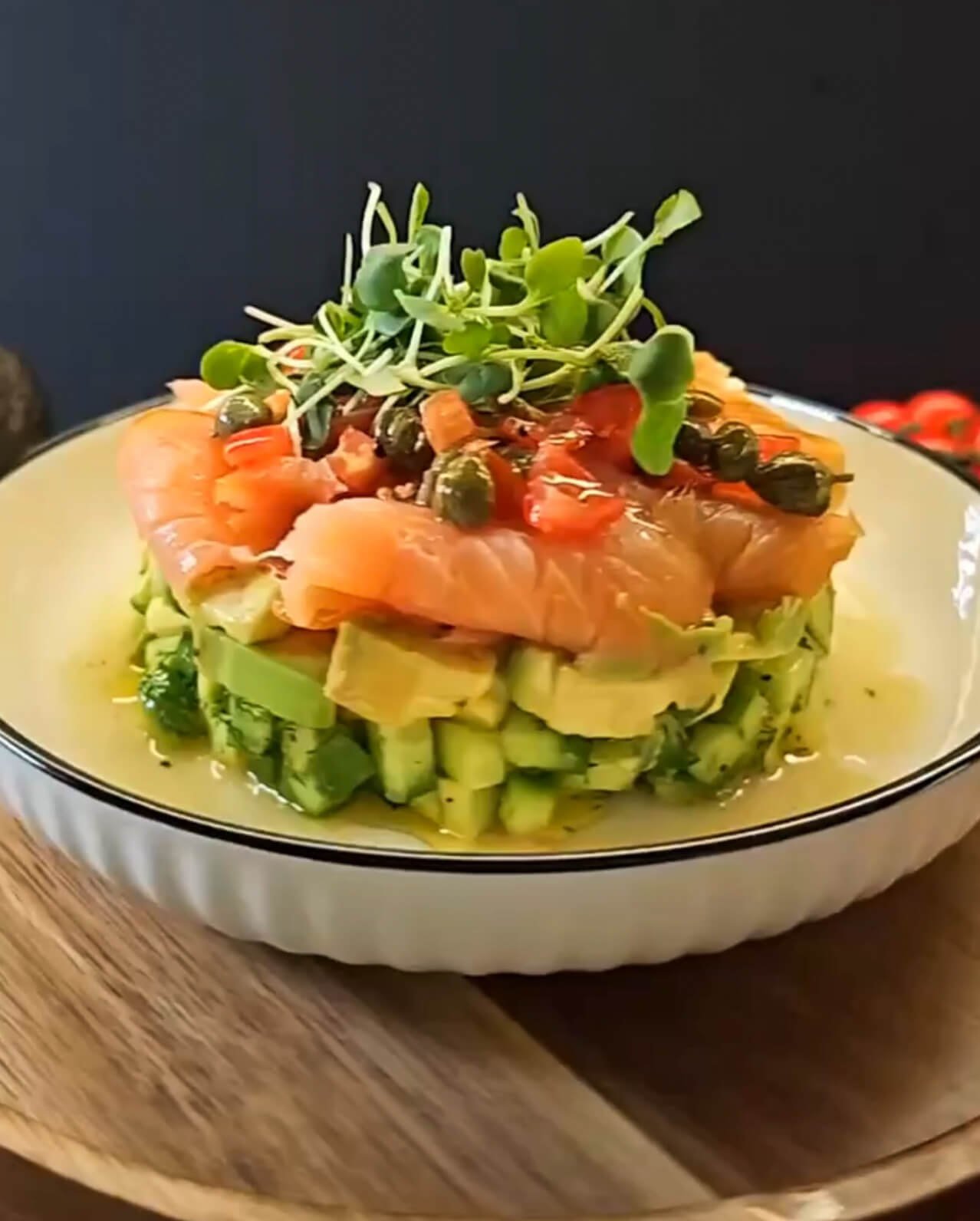 Elegant smoked salmon, avocado, and cucumber stack appetizer drizzled with lemon-caper dressing and garnished with microgreens