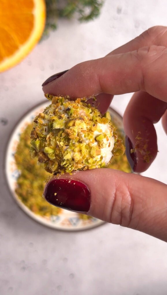 Close-up of pistachio-crusted goat cheese bonbon showing creamy cheese texture
