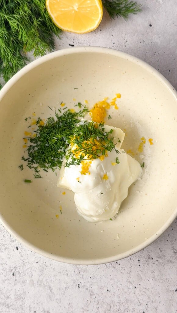 Greek yogurt, cream cheese, chopped dill, lemon zest, and salt in a bowl before mixing for the lemon-dill cream layer