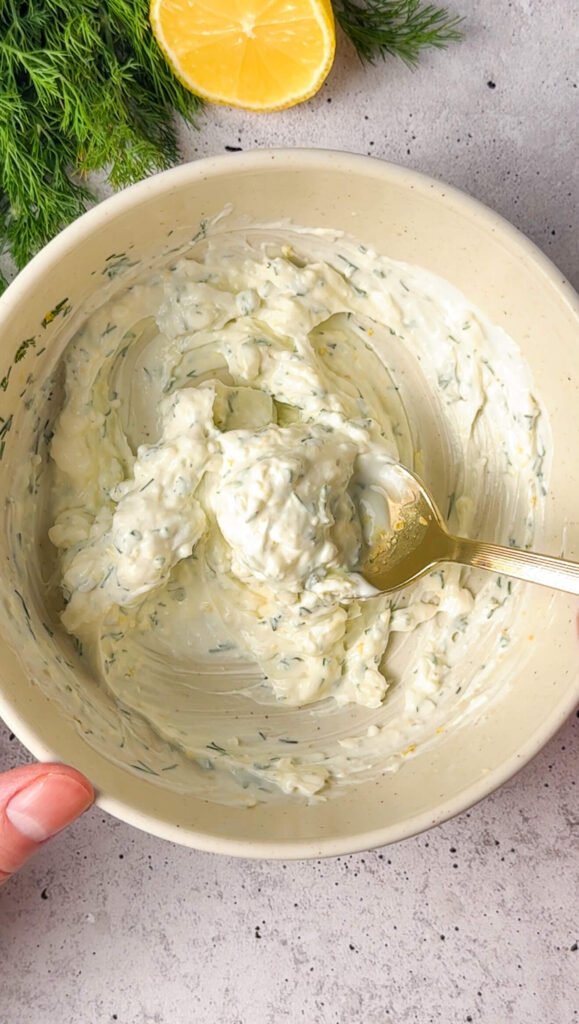 Whipped lemon-dill cream mixture in a bowl after combining yogurt, cream cheese, dill, and lemon zest.