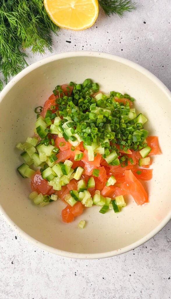 Bowl of finely diced smoked salmon, cucumber, and chives before mixing into a fresh salmon tartare
