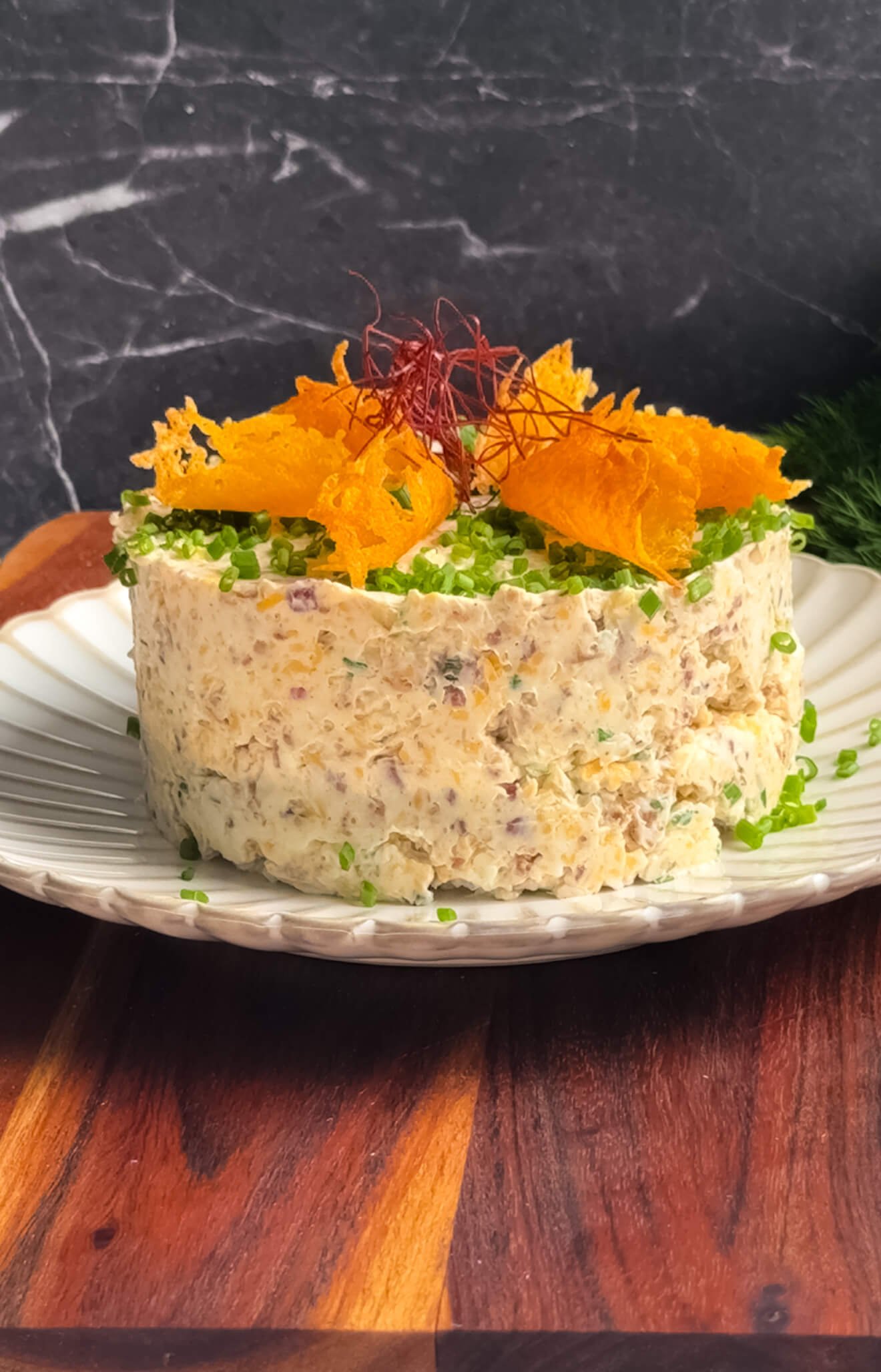 Million Dollar cheese stack with bacon, cheddar, toasted almonds, and fresh chives, garnished with crispy Parmesan chips