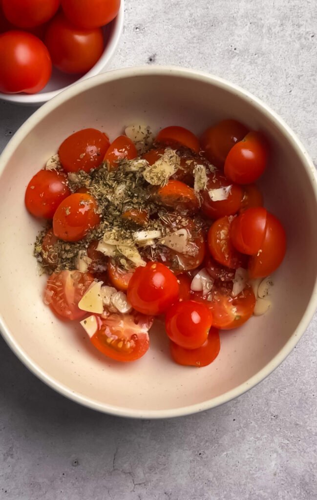 Cherry tomatoes mixed with olive oil, sliced garlic, and dried oregano for baked Boursin with tomatoes
