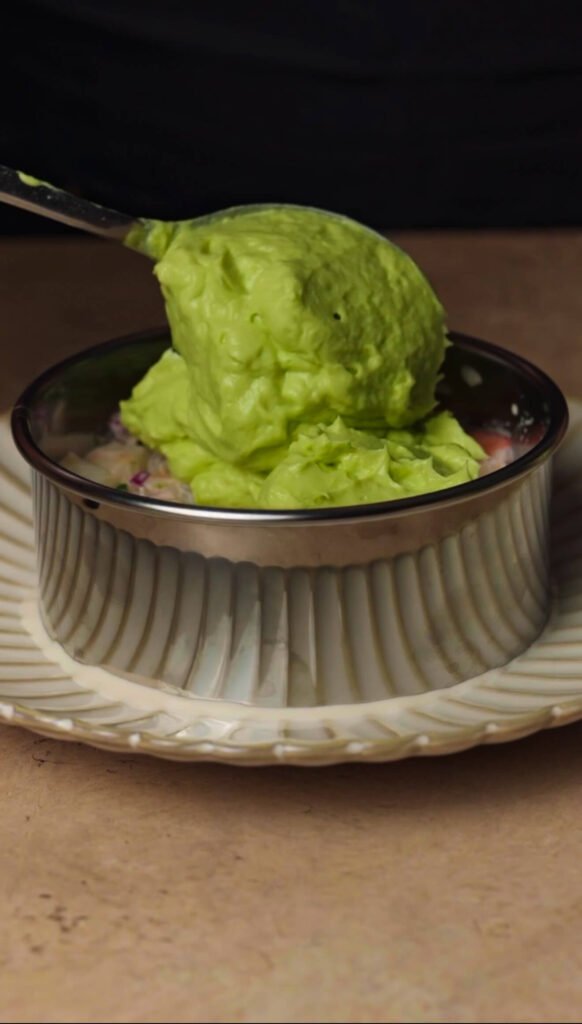 Spoonful of smooth avocado cream layered over shrimp appetizer