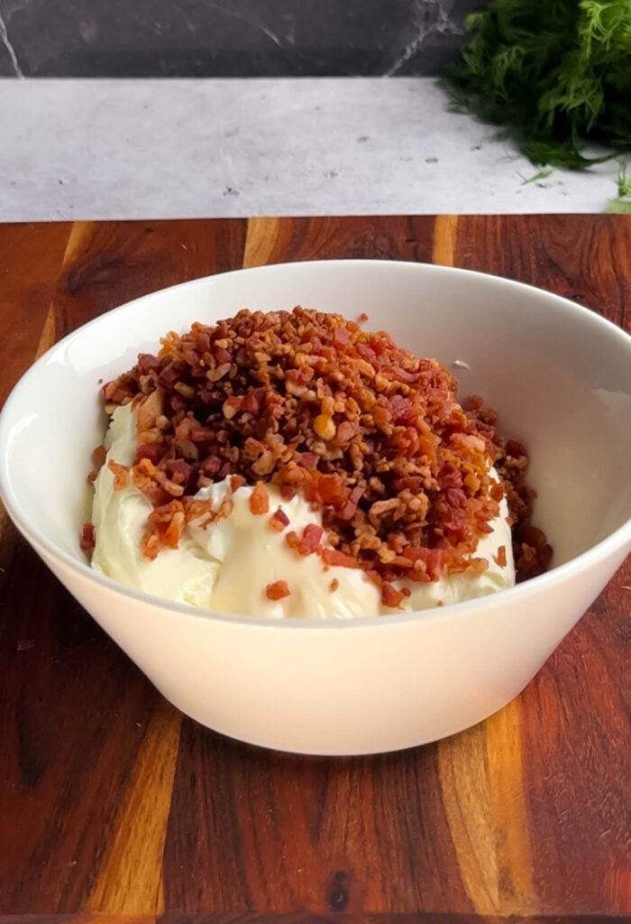 Cream cheese topped with bacon bits as the base for Million Dollar dip