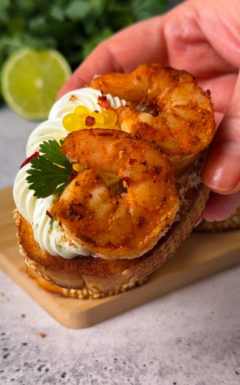Close-up of citrus shrimp crostini showing juicy shrimp and fruit caviar garnish