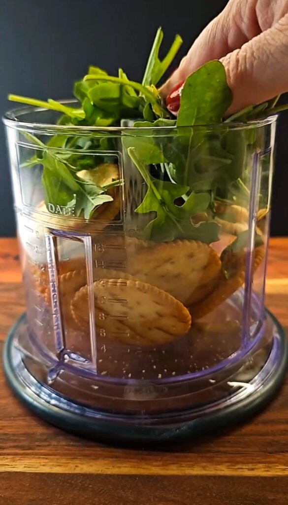 Ritz crackers and fresh arugula in a food processor for smoked salmon cheesecake crust