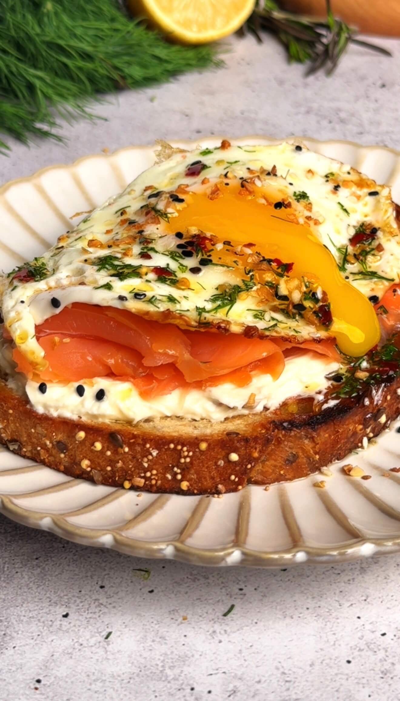 Close-up of creamy garlic confit toast topped with smoked salmon and a sunny-side-up egg with runny yolk
