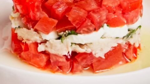 Layered Italian tuna tomato mozzarella salad with fresh basil oil served as an elegant appetizer