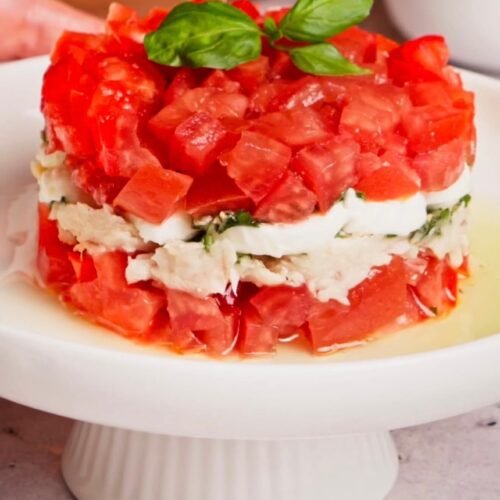 Layered Italian tuna tomato mozzarella salad with fresh basil oil served as an elegant appetizer
